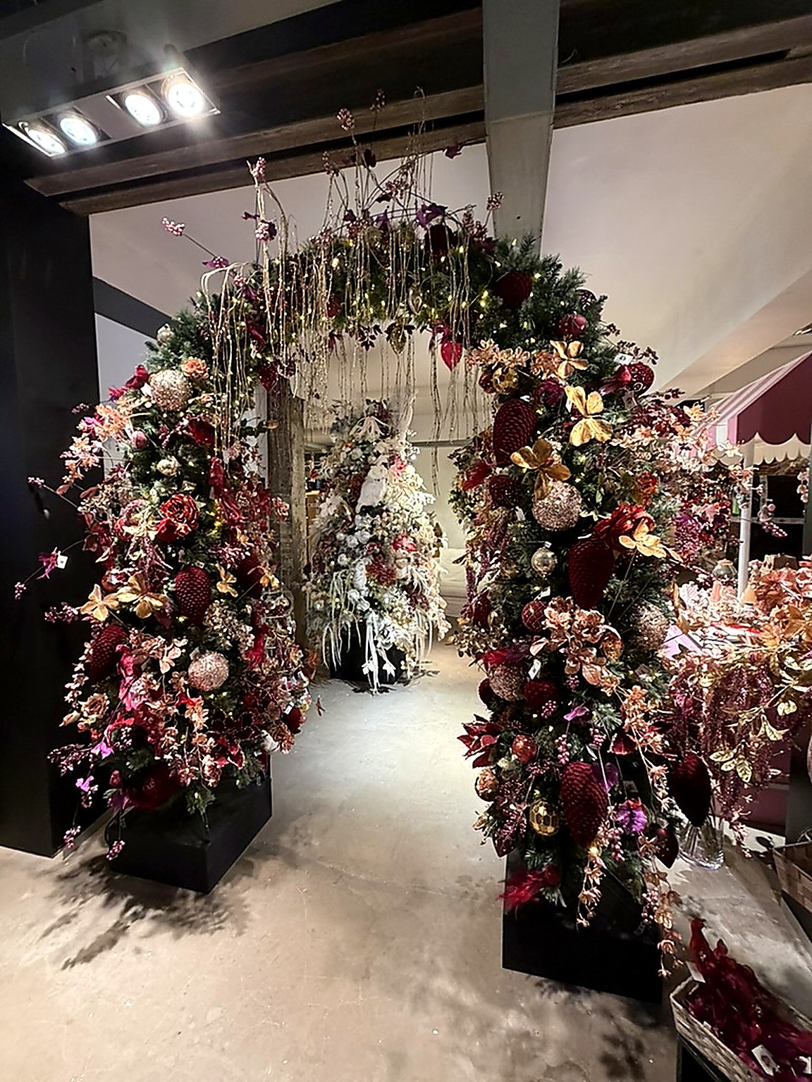 Arche de deux sapins bordeaux et or décorés de fleurs en verre, ouvrant sur une salle blanche chez DO-Wolf Arche de deux sapins bordeaux et or décorés de fleurs en verre, ouvrant sur une salle blanche chez DO-Wolf
