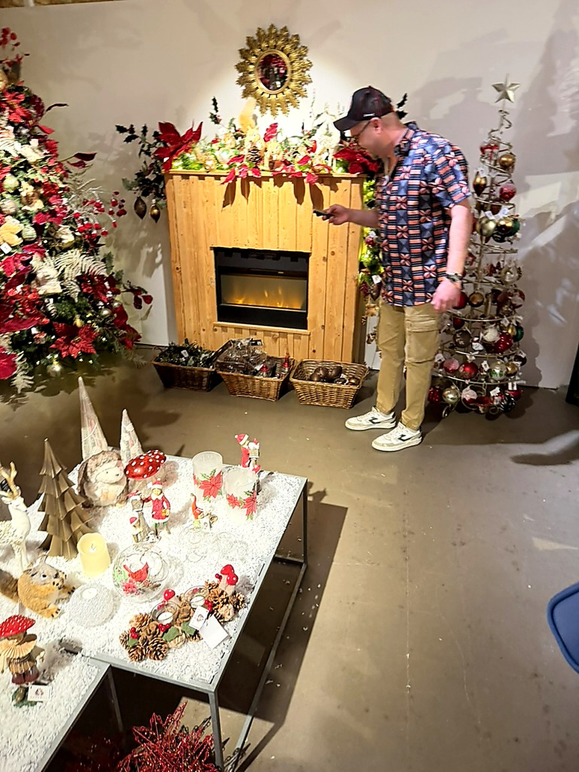 Damien Overputte règle une cheminée décorative entourée de sapins rouges et blancs chez DO-Wolf Damien Overputte règle une cheminée décorative entourée de sapins rouges et blancs chez DO-Wolf