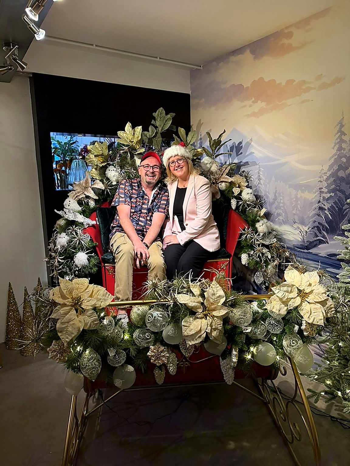 Damien Overputte et Floriane Bonnier assis dans un traîneau rouge décoré de poinsettias blancs Damien Overputte et Floriane Bonnier assis dans un traîneau rouge décoré de poinsettias blancs