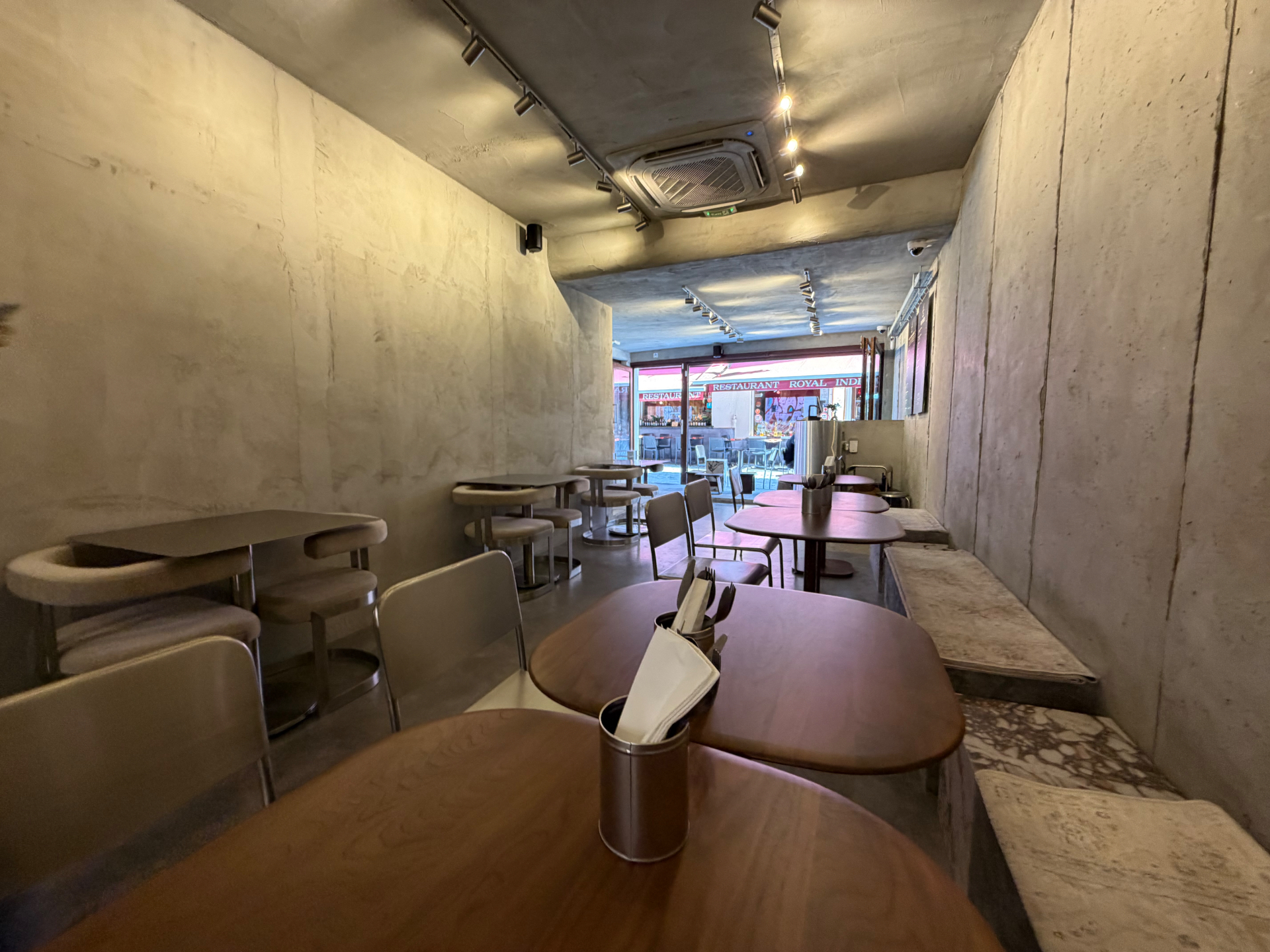 Salle de Lafeh Kanun : banquettes bouclées beige, tables ovales en bois et bancs en marbre calacatta