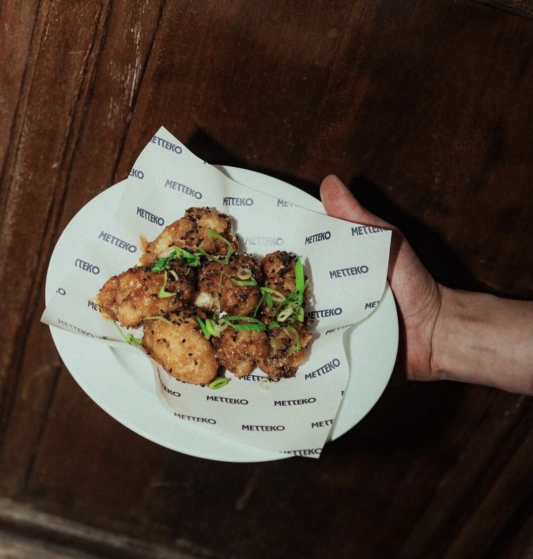 Assiette de karaage de poulet aux oignons verts et sésame noir, servie sur papier griffé METTEKO