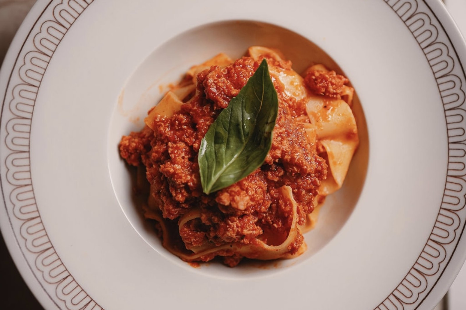 Paccheri al ragù et basilic frais dans une assiette signée Mina. Paccheri al ragù et basilic frais dans une assiette signée Mina.