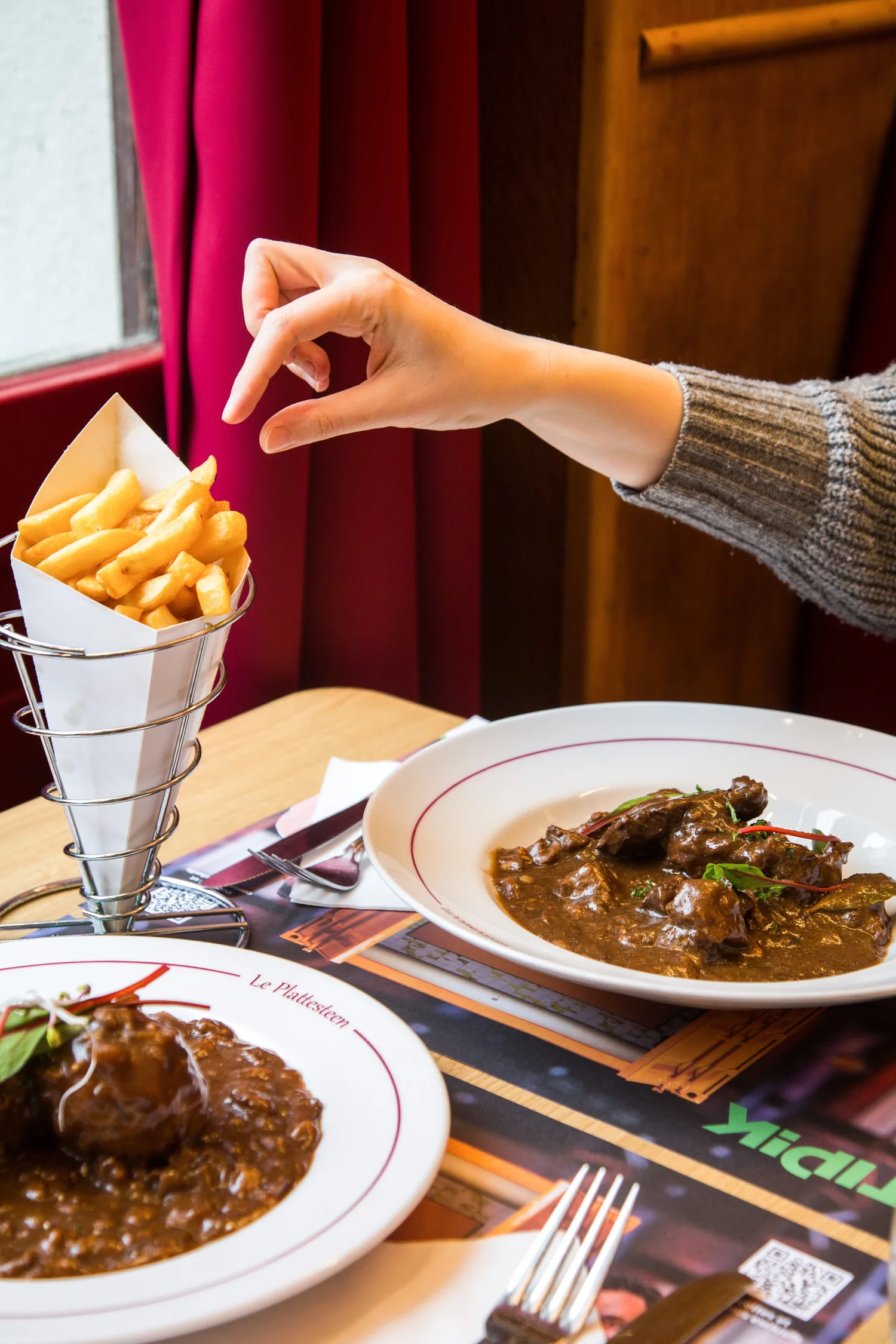 A table at Plattesteen with fries, stoemp-saucisse and Belgian dishes