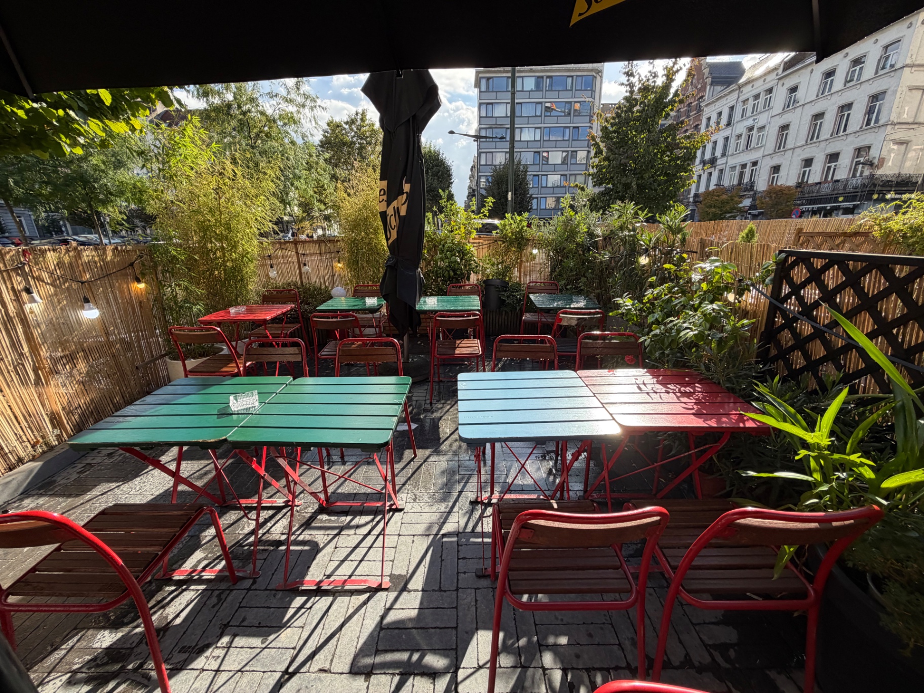 Garden terrace of Le Saint d’Hic III with colourful tables and bamboo